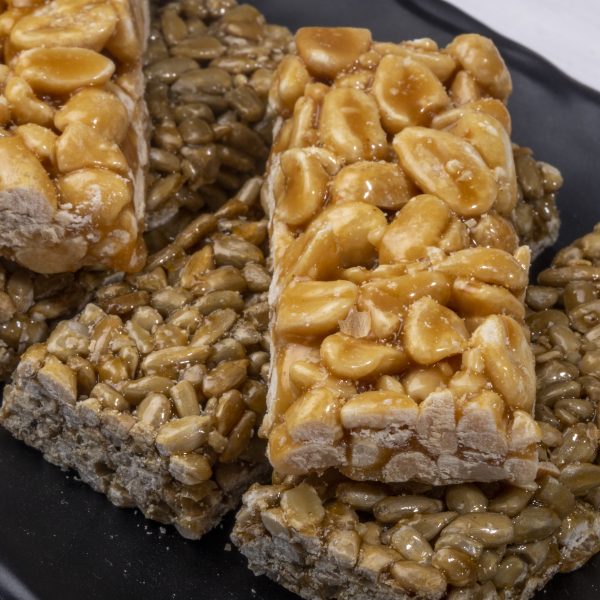 close up view of honey bars with peanuts and sunflower seeds on black background